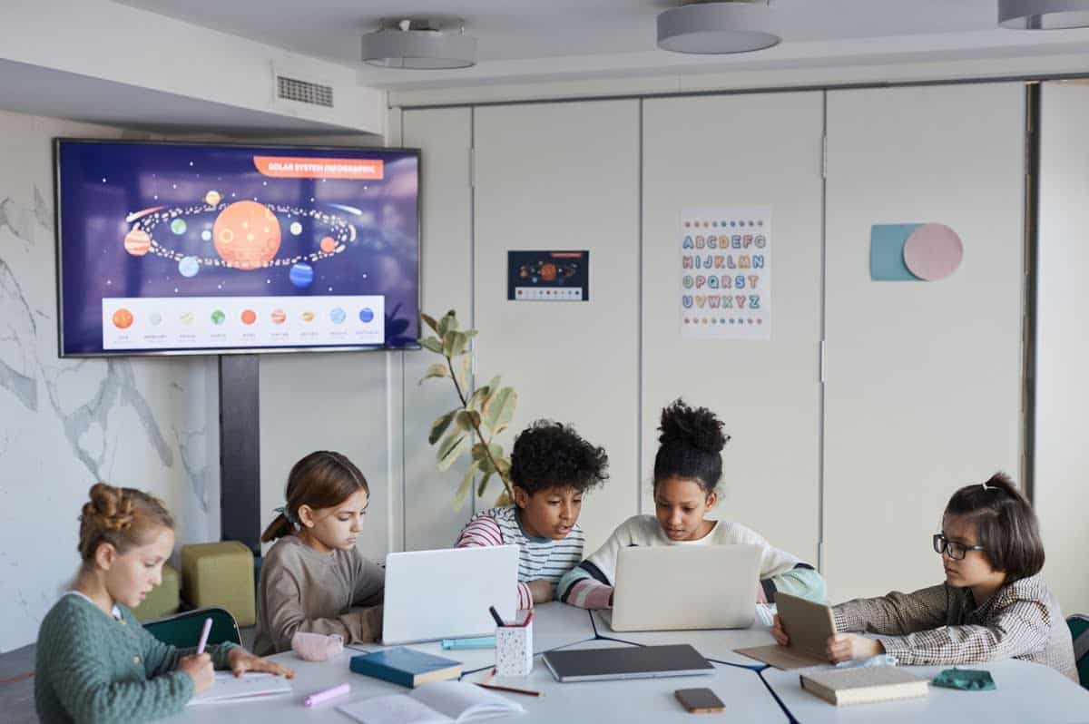 Diverse group of children at table in modern school, copy space